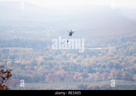 An Alabama National Guard UH-60 Black Hawk helicopter with Bambi bucket assembly provides aerial water delivery, at the request of the Alabama Emergency Management Agency, in support of forest fire suppression efforts in DeKalb County, Alabama, Nov. 19, 2016. National Guard Soldiers supported state and local firefighting efforts against multiple wildfires in North Carolina, South Carolina, Georgia, Tennessee, Alabama and Kentucky. ( Stock Photo