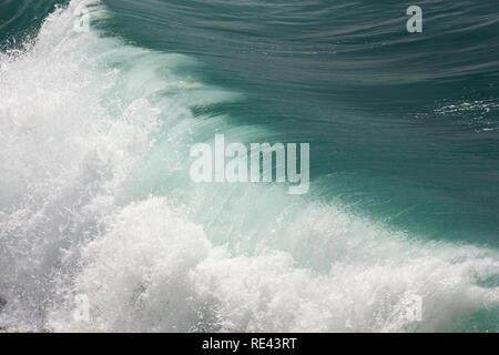 Wave transforms from a deep green colour to white as it crashes onto Porthleven beach Stock Photo