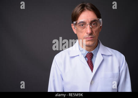 Mature handsome Italian man doctor wearing protective glasses Stock Photo