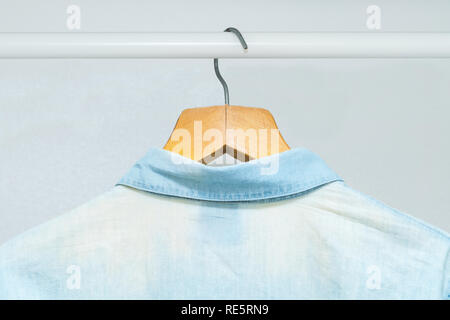 Worn out, bleached out old classic business shirt hanging in a wardrobe Stock Photo