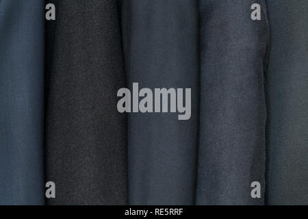 Different clothing textures of fine cloth at a tailor shop. Clothing design. Dark, black suits Stock Photo