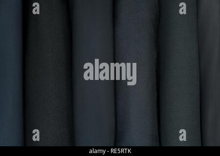 Different clothing textures of fine cloth at a tailor shop. Clothing design. Dark, black suits Stock Photo