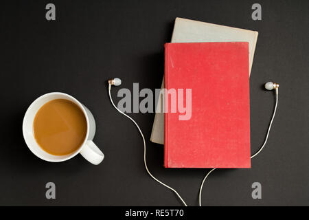 Audio book concept. Headphones, coffee and hard cover book over black table background. Top view with space for your text Stock Photo