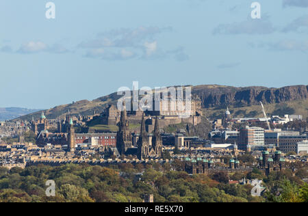 A cityscape photograph of the City of Edinburgh, Scotland, showcasing Edinburgh Castle and the Salisbury Crags on a clear day in Autumn. Stock Photo