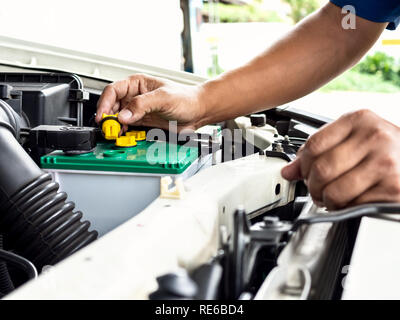 Technician hand opening the car battery for checking, repair or filling new distilled water in garage at car auto service for maintenance electrical s Stock Photo