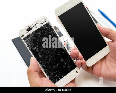 Close-up of cracked smartphone screen compare with new screen in technician hand on blurred smartphone component background Stock Photo