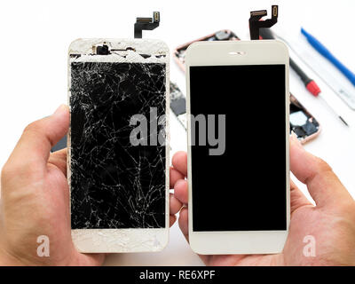 Close-up of cracked smartphone screen compare with new screen in technician hand on blurred smartphone component background Stock Photo