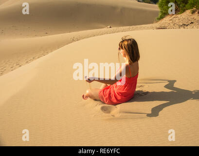 Girl in red relaxing in sandy desert Stock Photo