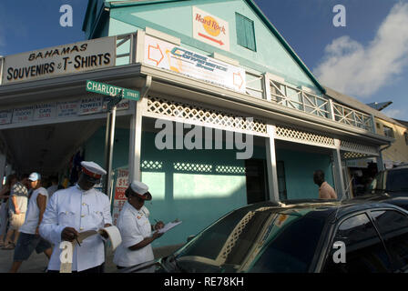 Police officers putting a fine next to shop of t-shirts, hats and souvenirs, Nassau, New Providence Island, Caribbean. Stock Photo