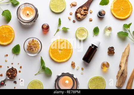 Bottles of essential oil with fresh citrus fruit, melissa, myrrh, white sandalwood and other ingredients Stock Photo