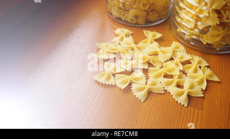 Pasta in the form of bows scattered from glass jar. Italian handmade pasta Stock Photo