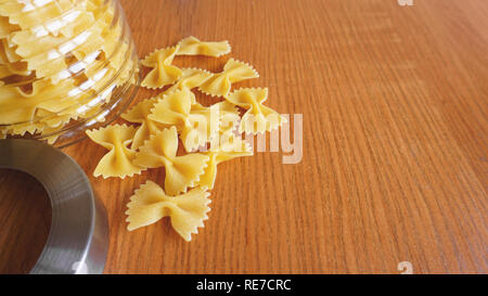 Pasta in the form of bows scattered from glass jar. Italian handmade pasta Stock Photo