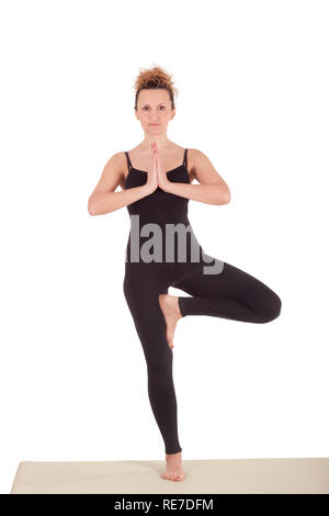 Slim woman practicing Tree yoga pose on mat in room near window - a Royalty  Free Stock Photo from Photocase
