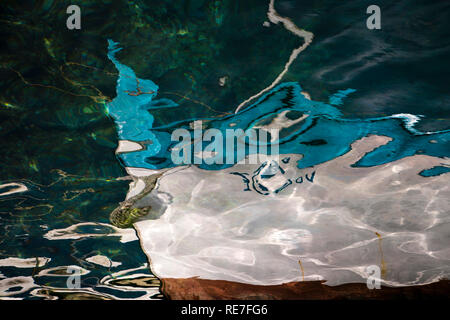 Blurry small wooden moored boat prow reflection in the shallow sea Stock Photo