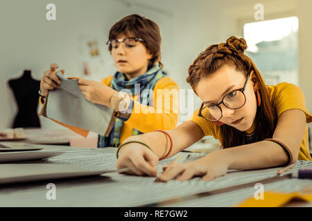 Future fashion designers using rulers while measuring fabrics Stock Photo