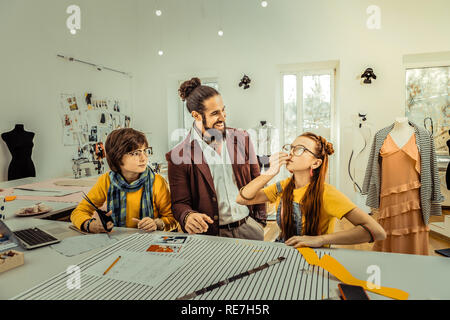 Bearded teacher wearing stylish jacket standing near students Stock Photo