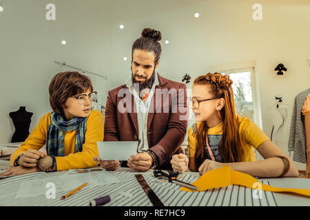 Children and fashion designer looking at photo of model Stock Photo