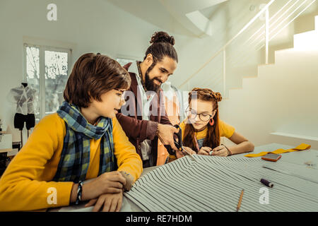 Dark-haired son wearing yellow sweater and scarf looking at father Stock Photo