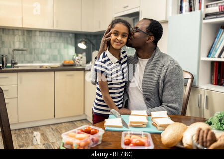 Loving father wearing glasses kissing his beautiful younger daughter Stock Photo