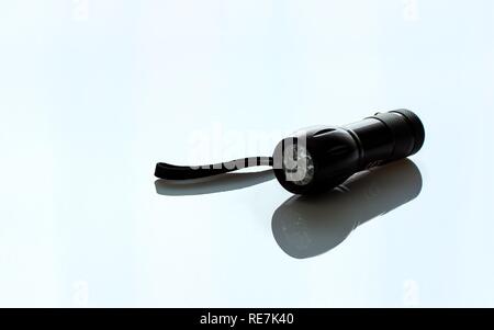 Hand held black metal flashlight isolated on light background Stock Photo