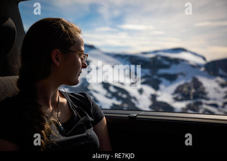 Tourist girl looking through car window over on mountains landscape next to Geirangerfjord and Dalsnibba viewpoint, Norway Stock Photo