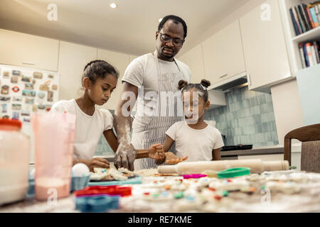 Daughters and their father enjoying cooking in the kitchen Stock Photo