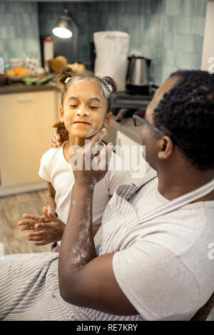 Caring father wearing glasses cleaning face of his lovely girl Stock Photo