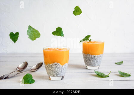 Chia seeds pudding with mango puree and flying mint leaves. Stock Photo