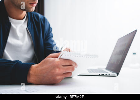 Concentrated manager working on laptop and reading information in modern spale office. Businessman sits at her desk and preparing project Stock Photo