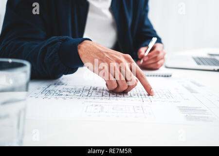 Coworker man using laptop and printer blueprint in modern office. Graph designer man working on workplace Stock Photo