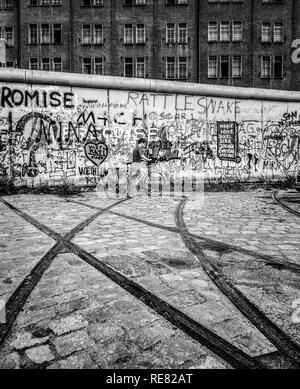 August 1986, Berlin Wall graffitis, tram track ending into wall, cyclist, East Berlin building, West Berlin side, Germany, Europe, Stock Photo