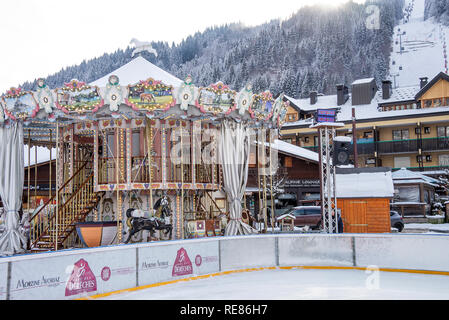 A Carousel Fairground Ride in the Snow Covered Town Centre Square of Morzine in the French Alps Haute Savoie Portes du Soleil France Stock Photo