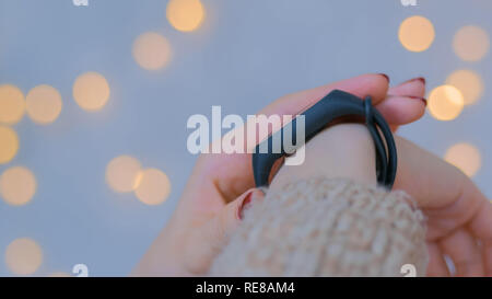 Young woman using wearable fitness tracker. Warm bokeh light background. Entertainment and technology concept. Close up shot of woman hand with smartwatch Stock Photo