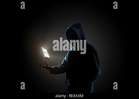 White smartphone with text 'HACKER' on screen floating above of hacker's hand in dark background. Finance, business, e-commerce or cyber crime concept Stock Photo