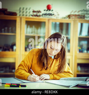 Young female college student in chemistry class, writing notes. Focused student in classroom. Authentic Education concept. Stock Photo