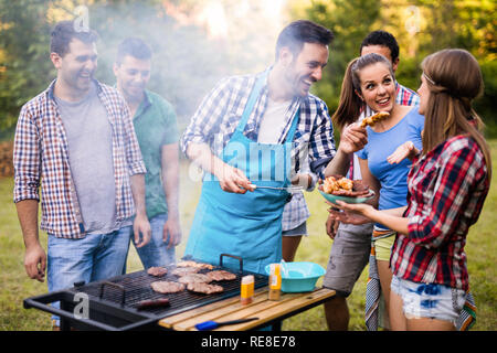 Happy friends enjoying barbecue party in forest Stock Photo