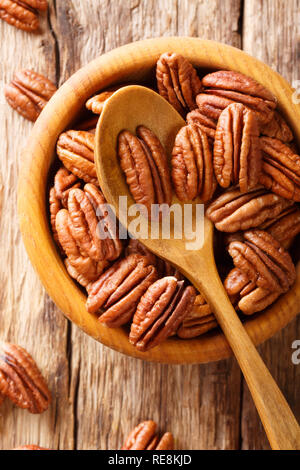 Bowl with pecan nuts on wooden table closeup. Vertical top view from above Stock Photo