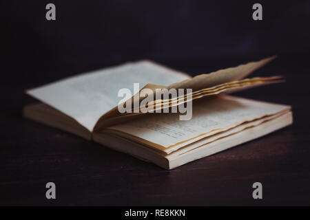 A dog eared paperback book on a dark background Stock Photo