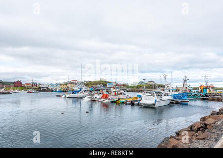 Stykkisholmur, Iceland - June 18, 2018: Town on cloudy overcast day and cityscape skyline of small fishing village on Snaefellsnes peninsula with boat