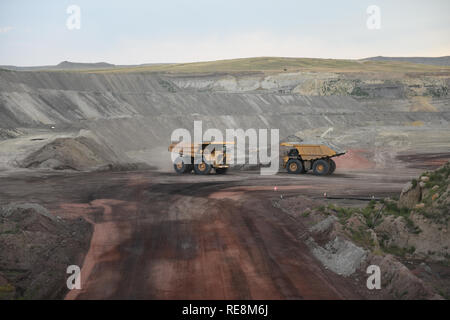 Giant sized yellow coal mining loader trucks passing each other inside an open pit coal mine in the Powder River Basin of Wyoming Stock Photo