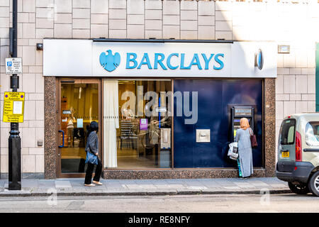 London, UK - June 21, 2018: Blue Barclays bank cash sign atm with people woman walking at banking branch office building entrance in Westminster on si Stock Photo