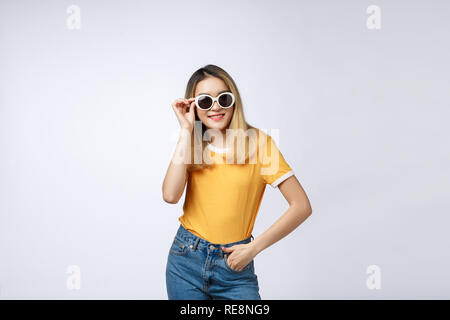 Young happy Asian woman smiling in fashionable dress and sunglasses and summer hat over whitebackground with copy space. Stock Photo