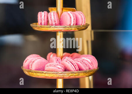Display of pile of gourmet colorful pink with white filling cream macaroons macarons on shelf afternoon tea tiered tray in bakery store shop cafe rest Stock Photo