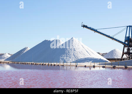 white salt mountains on blue background, with the pink lagoon in front of them due to the salt concentration Stock Photo