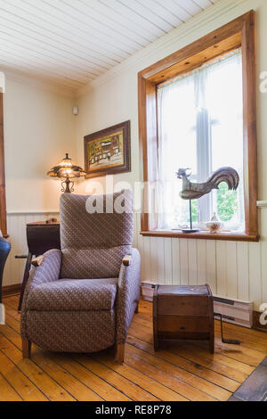 Cloth upholstered armchair in living room inside an old 1892 Canadiana cottage style home Stock Photo