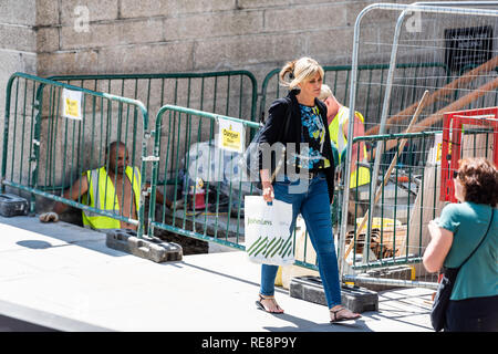 London, UK - June 22, 2018: High angle view of street road with busy people woman walking with shopping bag pedestrian on sidewalk by construction sit Stock Photo