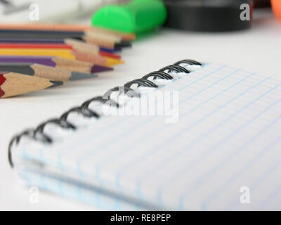 close-up of blurred image of checkered Notepad and pencils on white background Stock Photo