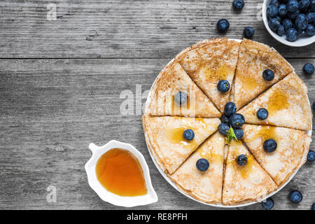 Pancakes with blueberries, maple syrup and mint leaf on top. Pile of thin homemade crepes with forest fruits. top view with copy space Stock Photo