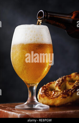 Full glass of fresh light beer with a pretzel on a stone stand Stock Photo