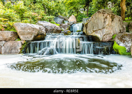 London, UK Kyoto Japanese Garden in Holland Park with green summer peaceful zen lake pond waterfall and long exposure smooth water Stock Photo